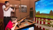 Two people are enjoying a simulated shooting game at an arcade.