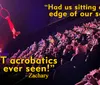 An acrobat performs on a ring high above an audience accompanied by enthusiastic reviews in bold text